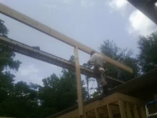Carpenter setting a ridge beam over a new addition frame — Ice Dam Removal by Roofing Brothers in Gardner