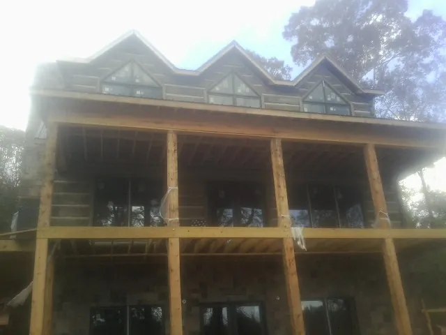 Dormers and porch framing on a large log home under construction — Roof Coating work by our crew in Gardner