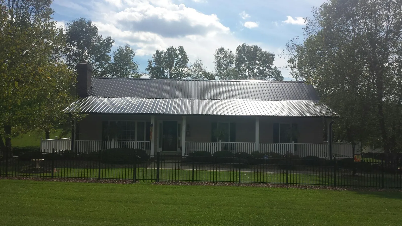 Gray metal roof on a brick ranch with a full width front porch — Gutter Guard Installation work by our crew in Gardner